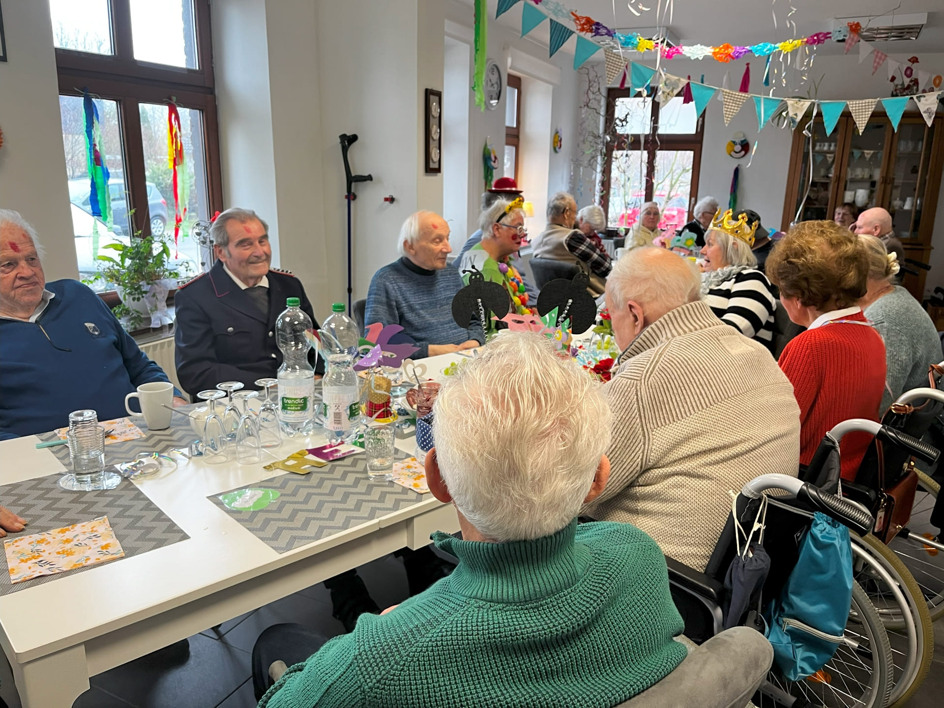 Senioren an einem großen Tisch im Esszimmer die Fasching feiern